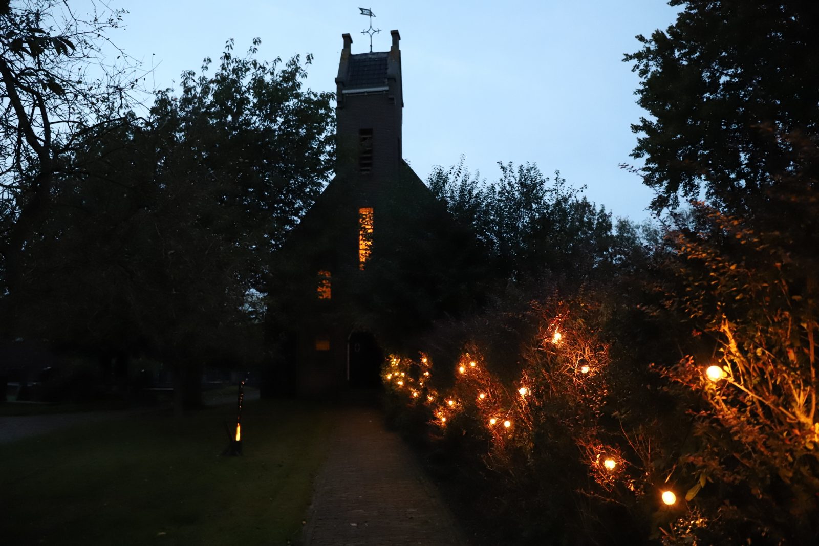 Verlicht pad naar 't Oude Kerkje in Garrelsweer bij avond