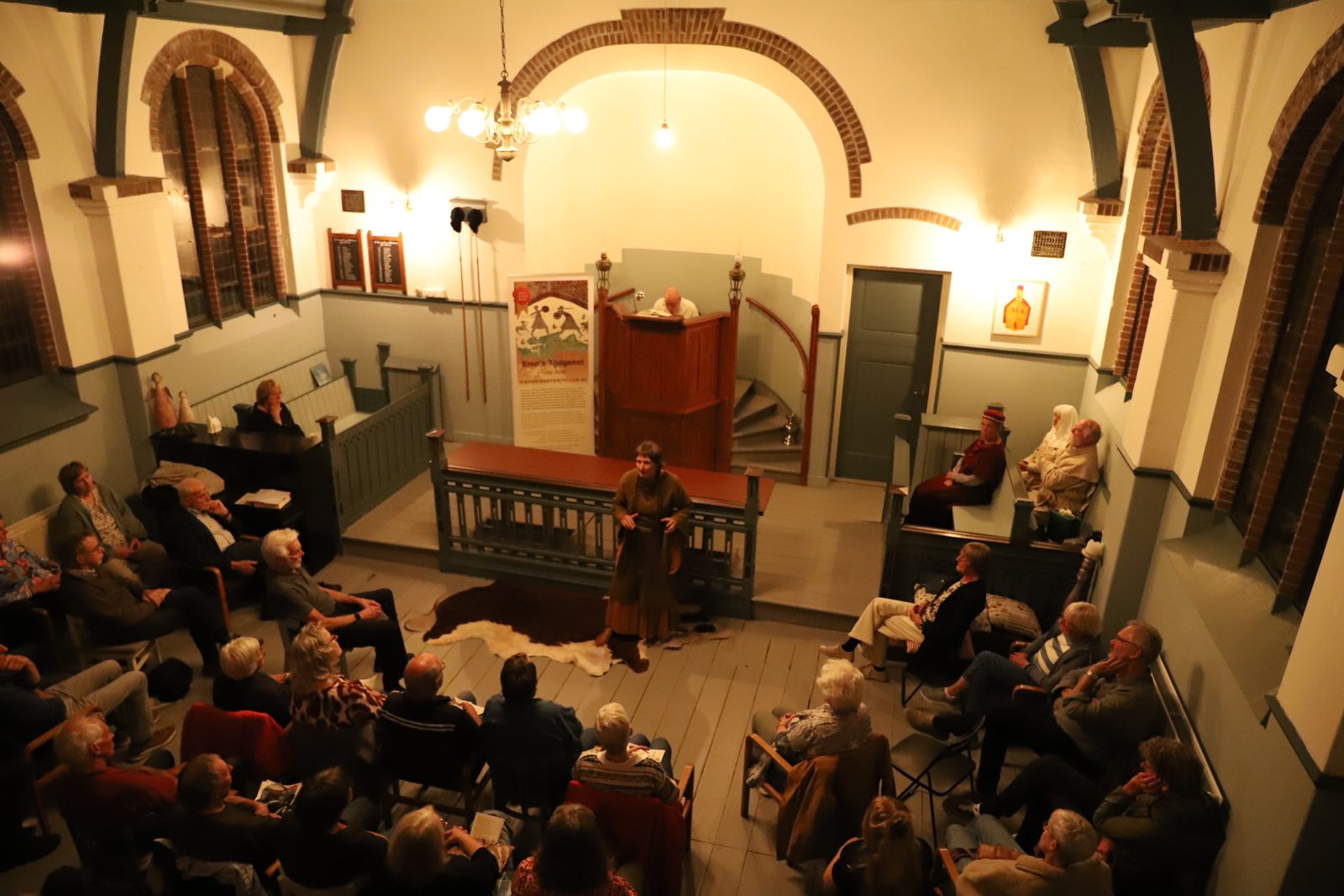 Vertelster in groen kostuum voor het publiek in 't Oude Kerkje