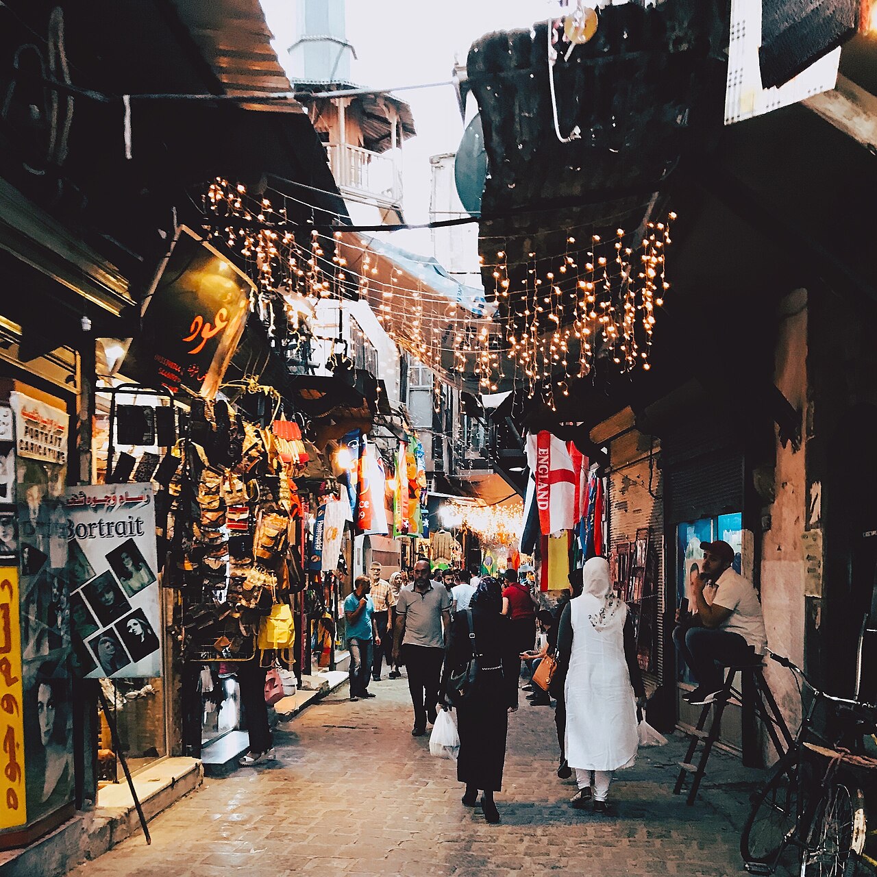 Een drukke straat met winkeltjes en lichtjes in de oude stad van Damascus
